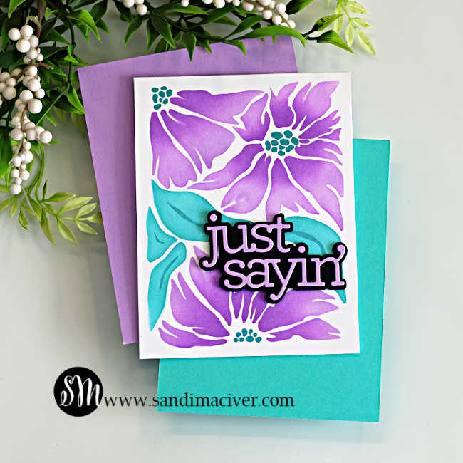 Ink blended card using the Friendly Blossoms stencil, featuring purple flowers, teal leaves, and a layered “just sayin’” sentiment on a white panel.