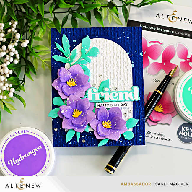 Layered magnolia die cut card with purple flowers, teal leaves, and embossed arch on a navy background, featuring Altenew Delicate Magnolia dies and Hydrangea ink with “friend” birthday sentiment