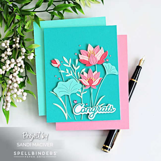 Lotus flower card in pink and teal with layered die cut blooms, leafy stems, and a bold “congrats” sentiment, accented with gems on a teal background
