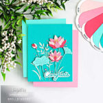 Lotus flower card in pink and teal with layered die cut flowers, leafy stems, and “congrats” sentiment on a blended teal background, handmade cardmaking idea