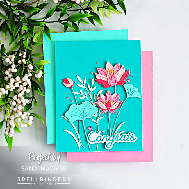 Layered lotus flower card in pink and teal with dimensional die cut flowers and leaves, “congrats” sentiment, and sparkling gems on a teal background