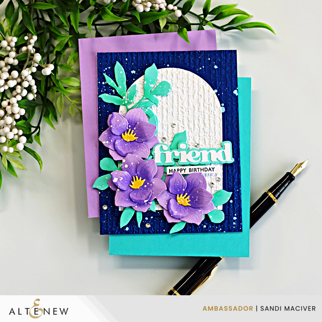 Magnolia die cut card with layered purple flowers, teal leaves, and embossed linen arch on a navy background with splatter, featuring a “friend” happy birthday sentiment and Altenew branding
