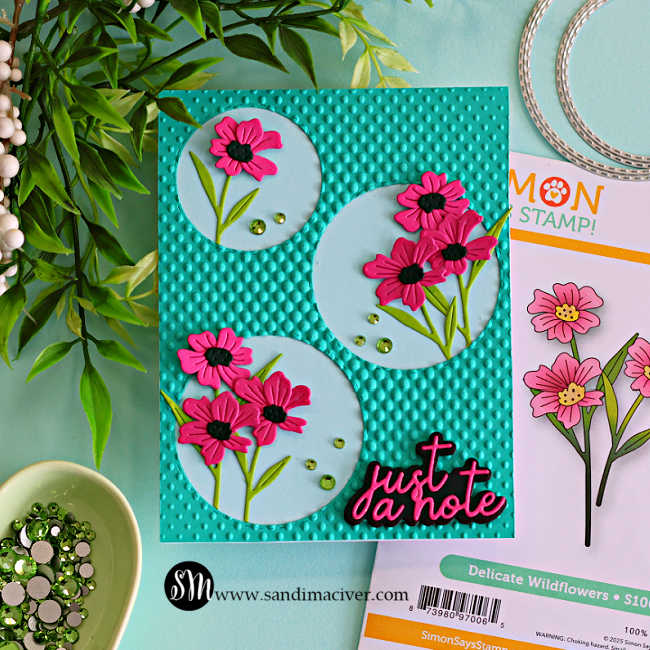 Handmade die cut floral card featuring pink flowers in stitched circle frames on a teal halftone embossed background with “just a note” sentiment and coordinating wildflower die set.