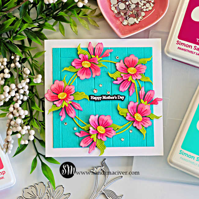 Square Mother’s Day card featuring a floral wreath of pink ink-blended die cut flowers and green leaves on Audrey Blue embossed cardstock with a wooden plank texture and a “Happy Mother’s Day” sentiment.