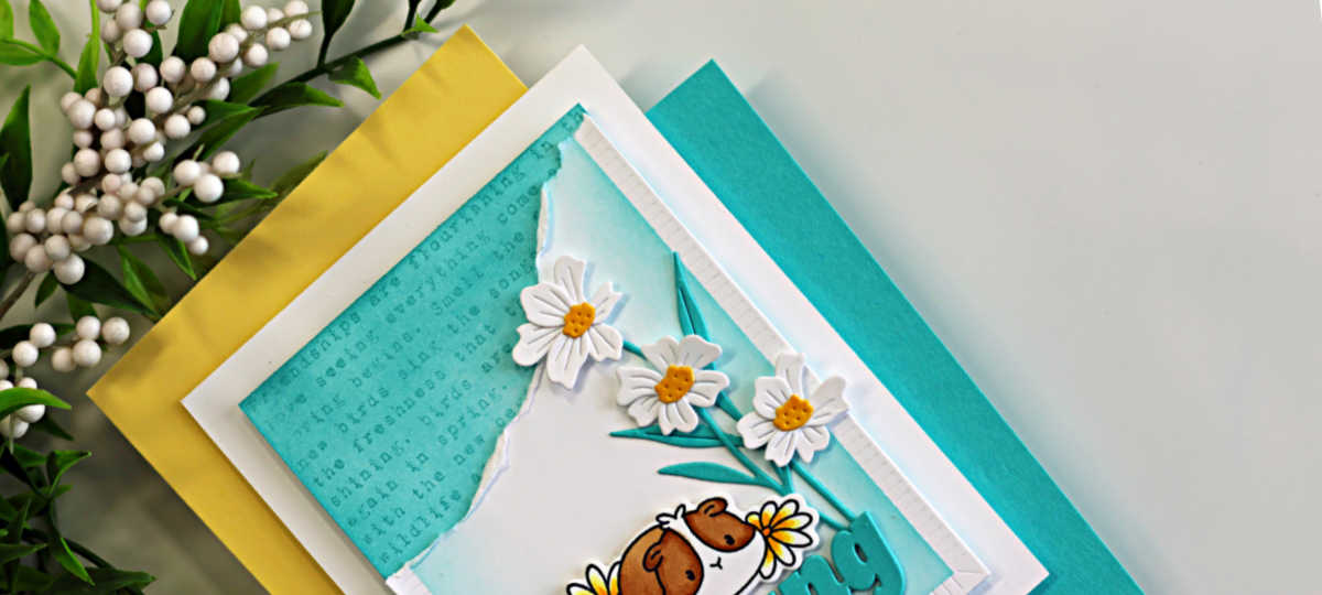 Close-up of a clean and simple handmade card featuring a turquoise ink-blended background with torn paper edges, white die cut daisies, and layered texture details. The card uses minimal colors with Audrey Blue accents and subtle tone-on-tone stamping for added interest.