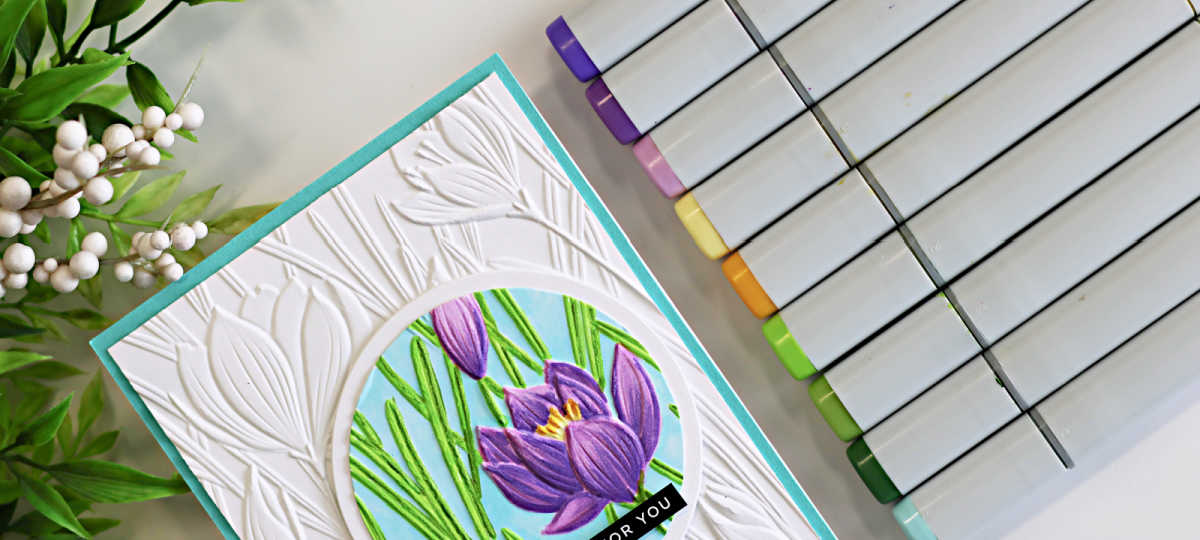 Handmade spotlight technique card featuring the Simon Says Stamp Crocus Field embossing folder with a circular crocus floral focal point colored using purple and green Copic markers on a white embossed background with aqua card base.