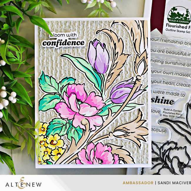 Elegant handmade floral card created with the Altenew Build-A-Garden: Flourished Flora set, featuring pink peonies, lavender tulips, aqua green leaves, and warm beige botanical flourishes over a textured ivory embossed background. The card includes the sentiment “bloom with confidence” and is photographed beside the coordinating stamp set.