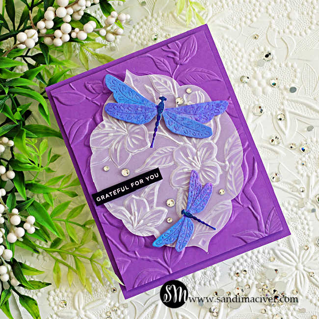 Elegant handmade dragonfly card featuring embossed vellum floral layers over a rich purple embossed background with shimmering blue and violet dragonflies created using Lindy’s Magicals in Sweet Violet Purple and Hydrangea Blue.