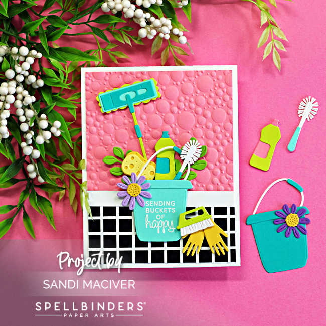 Retro-inspired handmade Spellbinders Shiny New Day card featuring a pink embossed bubble background, black-and-white checkered floor pattern, and colorful die cut cleaning supplies including a mop, sponge, spray bottle, scrub brush, gloves, and bucket with the sentiment “Sending Buckets of Happy.”