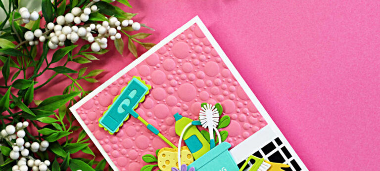 Retro-inspired handmade cleaning-themed card featuring a pink embossed bubble background, black-and-white checkered floor pattern, and colorful die cut cleaning tools including a mop, sponge, spray bottle, gloves, and bucket created with the Spellbinders Shiny New Day release.