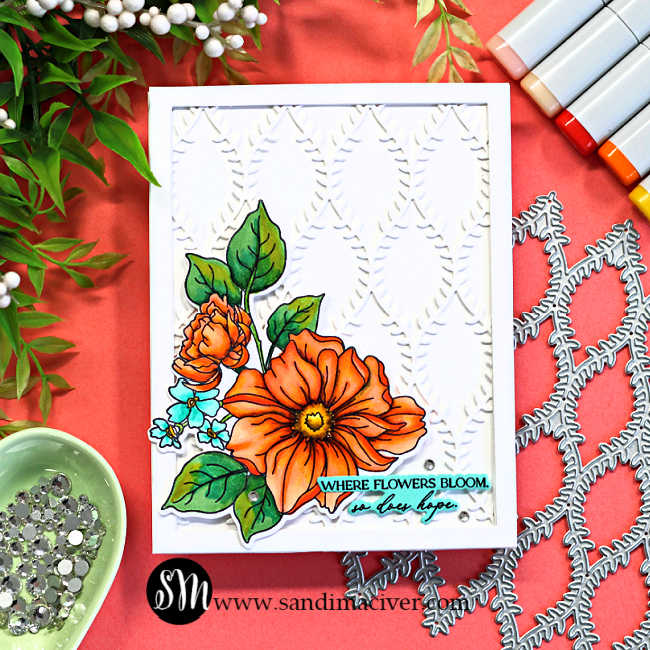 Handmade floral card featuring a framed white lattice background created with the Simon Says Stamp Willowweave Plate and colorful Copic-colored flowers from the Blooms of Encouragement stamp set. The dimensional card design includes bright orange florals, layered die cuts, a clean white frame, and a soft coral crafting backdrop with Copic markers and embellishments.