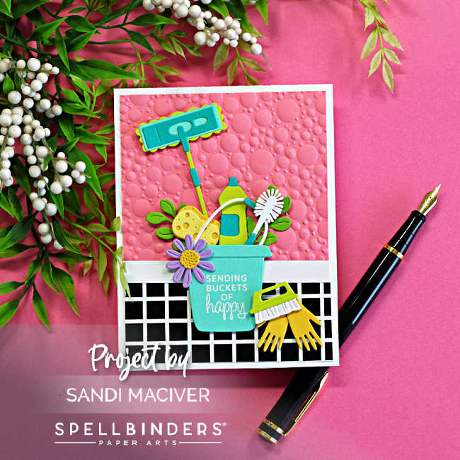 Retro-inspired Spellbinders Shiny New Day handmade card featuring colorful die cut cleaning supplies in a turquoise bucket with a pink embossed bubble background, black-and-white checkered floor pattern, and the sentiment “Sending Buckets of Happy.”