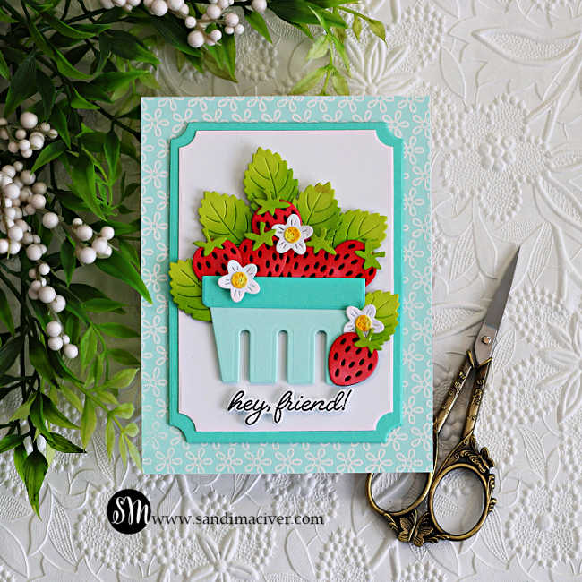 Handmade strawberry basket friendship card featuring layered die cut strawberries, ink blended green leaves, and tiny white flowers arranged inside a soft aqua basket. The background features the Petite Petal Background stamp white heat embossed onto Seaside cardstock with layered A2 Notched Rectangle frames and a “hey friend!” sentiment.