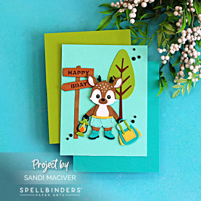 Cute summer camp birthday card featuring a layered die cut woodland deer holding a lantern beside a Happy Birthday sign and backpack, created with the Spellbinders Summer Camp Collection by Alli Fraser using teal, green, brown, yellow, and orange cardstock.