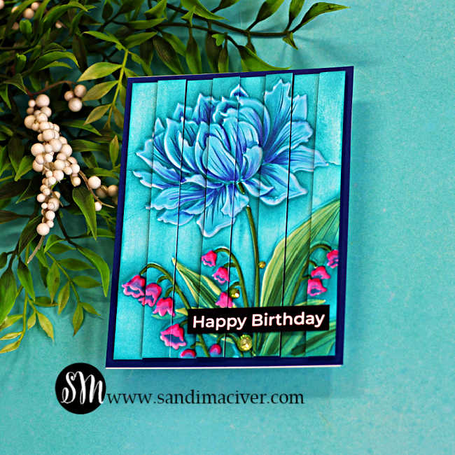 Handmade birthday card featuring the Colored Embossed Double Vision Technique using the Peony Trio embossing folder. The blue peony is colored with Copic markers and set against a weathered aqua barnwood background created with ink dragging. Alternating raised strips create the dimensional Double Vision effect, while pink lily of the valley flowers, a black "Happy Birthday" sentiment, and green gems complete the design.