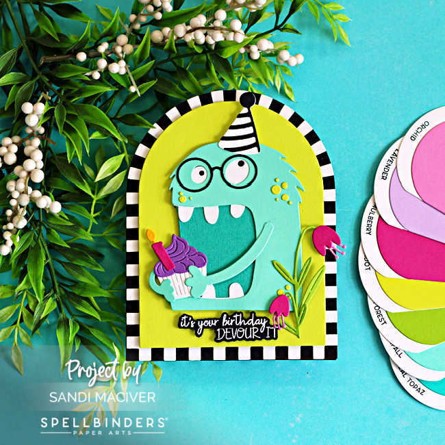 Colorful shaped birthday card featuring a turquoise Chompster monster holding a cupcake with a lit candle. The monster wears a black-and-white striped party hat and is framed inside a bright lime green arch with a striped border. Pink flowers and green foliage decorate the scene, while the sentiment reads, "It's your birthday, DEVOUR IT!" The card is photographed on a turquoise background with greenery and coordinating cardstock color swatches.