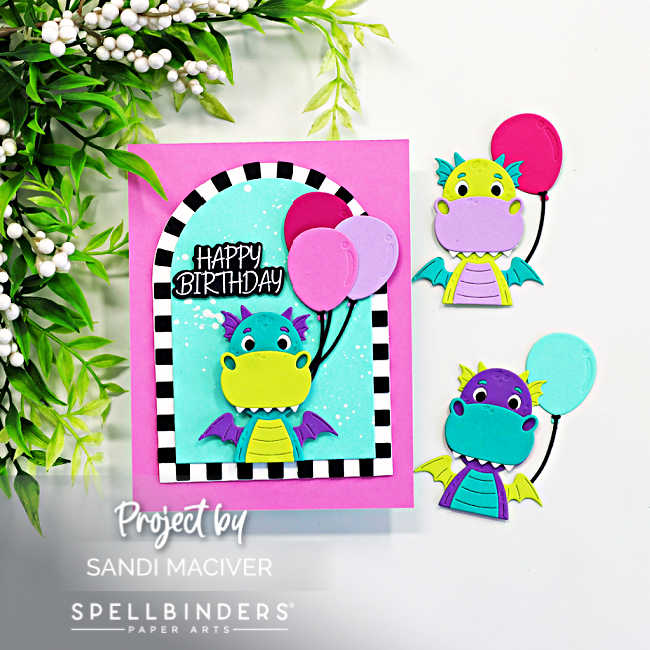 Cute dragon birthday card created with the Spellbinders Party Time Dragon die set featuring a turquoise dragon holding pink balloons inside a bold black and white striped arch window on a bright pink card base. Two additional colorful dragon die cuts are displayed beside the card on a clean white background.