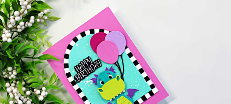 Bright and playful dragon birthday card featuring the Spellbinders Party Time Dragon die set with colorful balloons, a turquoise ink-blended background, bold black and white striped arch frame, and a happy birthday sentiment on a vibrant pink card base.