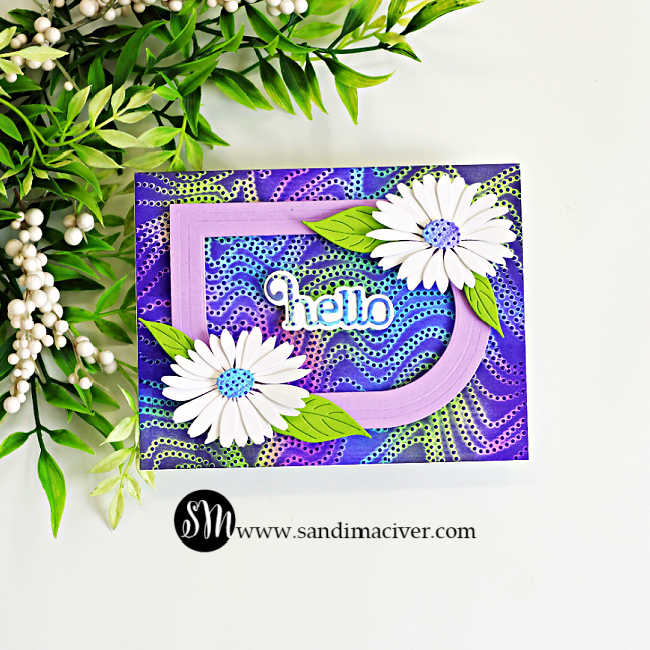 Handmade greeting card featuring the Embossed Joseph's Coat Technique with an ink-blended embossed background in vibrant shades of purple, blue, and green. A layered lavender frame, two white daisy die cuts with green leaves, and a dimensional "hello" sentiment create a clean, elegant floral design.