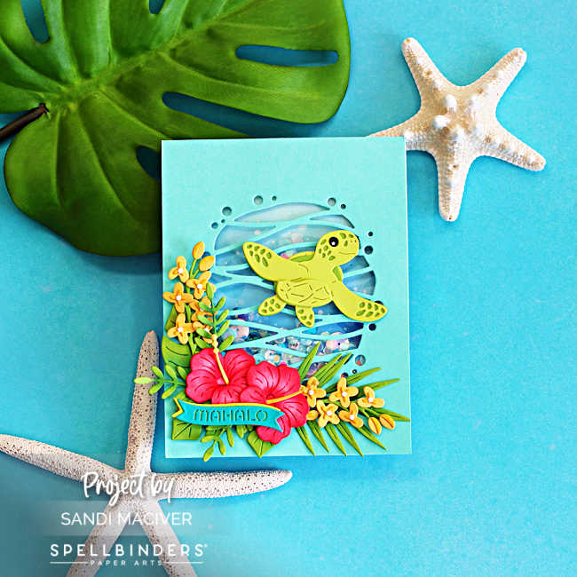 Handmade tropical shaker card featuring a layered green sea turtle swimming over a blue ocean-inspired shaker window filled with sequins. Bright pink hibiscus flowers, yellow tropical blooms, and lush green foliage decorate the bottom of the card. The card is photographed on a turquoise background with tropical monstera leaves and starfish accents, creating a Hawaiian paradise theme.