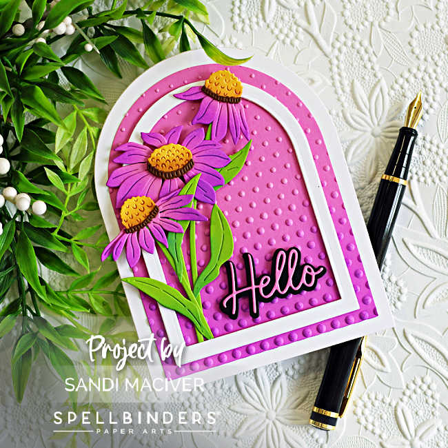 Handmade arched greeting card featuring layered purple wild coneflowers with bright green leaves and golden-yellow flower centers. The flowers are arranged inside a white arched frame over a vibrant pink embossed background created with the Layered Cascading Dots Embossing Folder. A bold black "Hello" sentiment anchors the design, while a white embossed floral background, greenery, and a black fountain pen add an elegant garden-inspired feel. 🌸💗💜