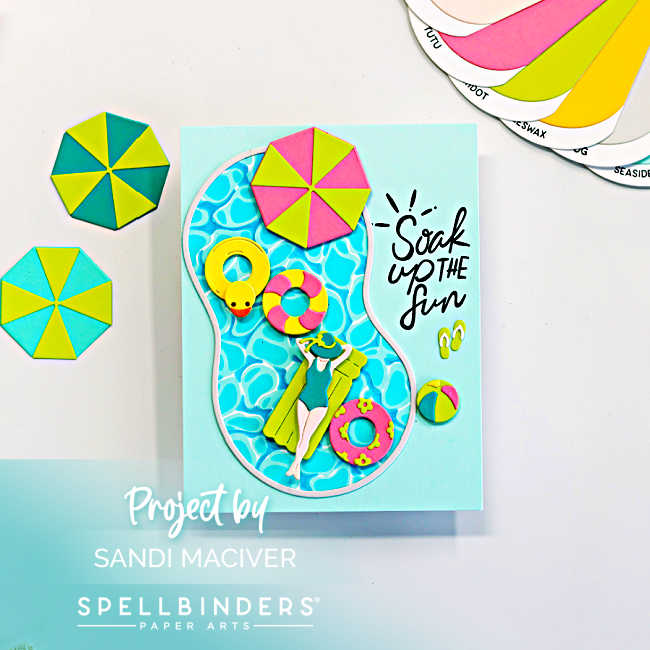 Handmade summer pool card featuring a die-cut swimming pool filled with bright aqua water, colorful floaties, a yellow rubber duck tube, beach umbrella, flip-flops, and a relaxing swimmer. The card includes the sentiment “Soak Up the Fun” on a soft aqua background with beach-inspired seashell and starfish accents.