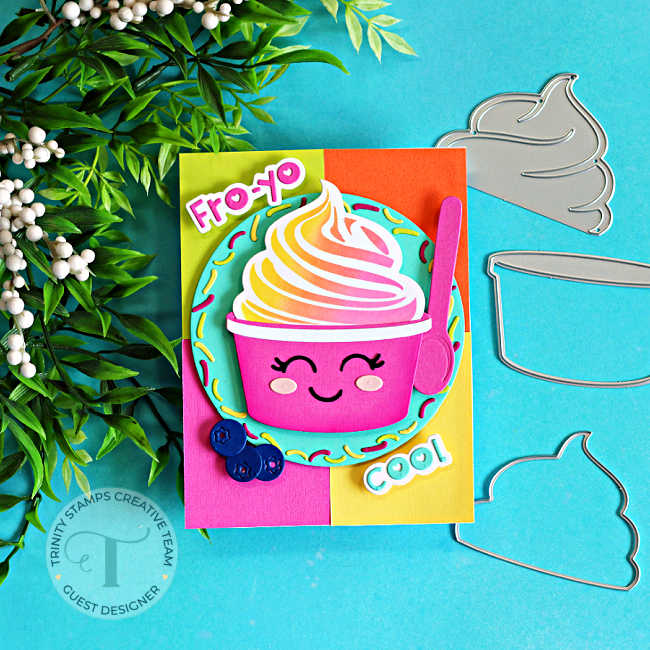 Handmade summer card featuring a smiling frozen yogurt cup from the Trinity Stamps Fro-Yo Friends release. The fro-yo is blended in soft pink, yellow, and orange shades and paired with a bright pink spoon. It sits on a colorful color-blocked background of pink, yellow, orange, and aqua cardstock, framed by a sprinkle-covered circle. Blueberry embellishments and playful "Fro-Yo" and "Cool" sentiments complete this cheerful card design.