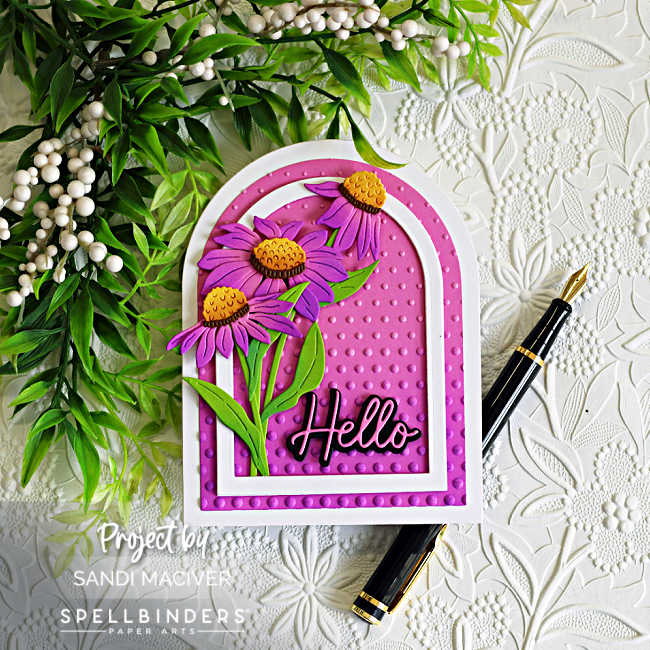 Handmade arched greeting card featuring layered purple wild coneflowers with bright green leaves and golden-yellow flower centers. The flowers are arranged inside a white arched frame over a vibrant pink embossed background created with the Layered Cascading Dots Embossing Folder. A bold black "Hello" sentiment anchors the design, while a white embossed floral background, greenery, and a black fountain pen add an elegant garden-inspired feel. 🌸💗💜