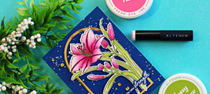 Dark and Moody handmade floral card featuring the Altenew Leaning Lily stamp, stencil, and die bundle. A vibrant pink lily is framed by a gold arched die cut on a deep navy blue ink-blended background with gold splatter and sequins, alongside Altenew Mossy Meadow Fresh Dye Ink and a blending brush.