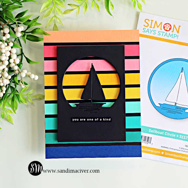 Handmade retro sailboat card featuring colorful sunset-inspired cardstock stripes in coral, pink, yellow, aqua, and navy. A black sailboat silhouette is framed inside a circular die-cut window, with the Simon Says Stamp Sailboat Circle die packaging displayed beside the finished card.