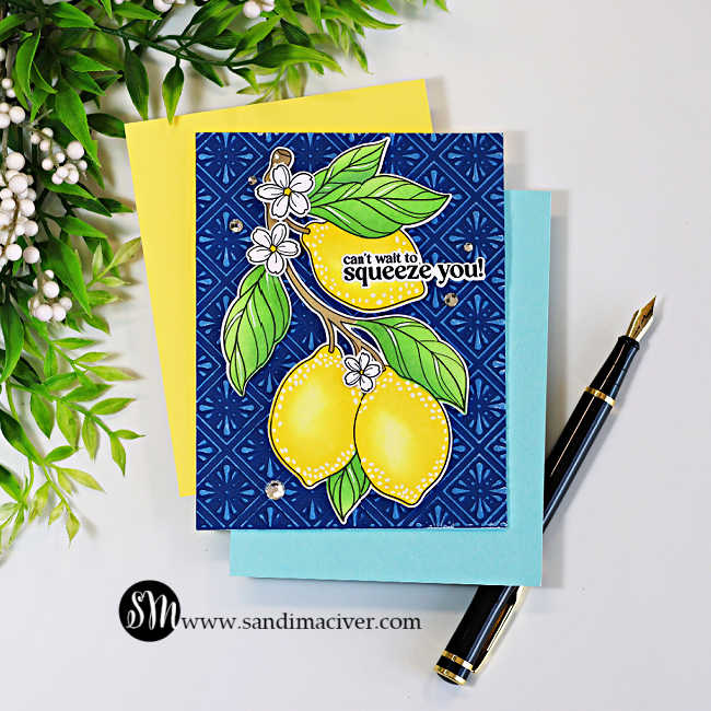 A handmade greeting card featuring two bright yellow lemons with green leaves and delicate white blossoms, layered over a deep navy blue embossed background with white highlights that resemble Spanish ceramic tiles. The sentiment, "can't wait to squeeze you!", is placed across the top lemon. The card is displayed on layered yellow and light blue cardstock beside a black fountain pen, with decorative greenery framing the upper left corner on a clean white background.