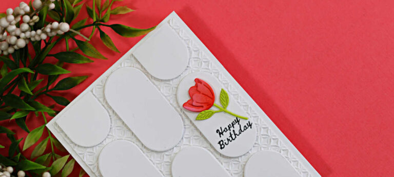 Handmade white birthday card featuring a geometric pattern created with oval die cuts over an embossed background, accented with a coral flower and Happy Birthday sentiment.