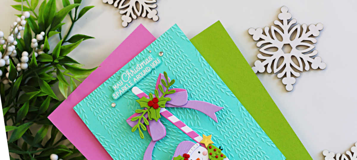 Interactive Christmas card featuring a swinging snowman suspended from a pink and white candy cane on a cozy aqua knit embossed background, accented with a lavender bow, holly leaves, and bright Christmas colors.