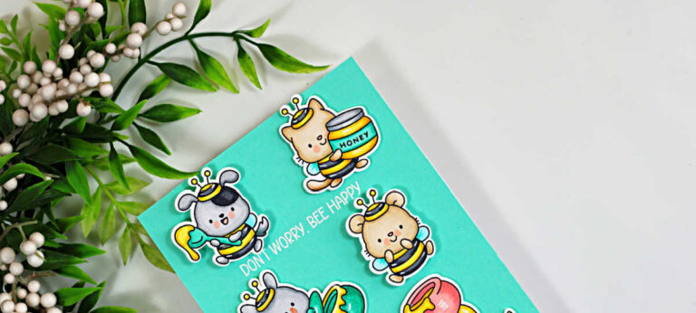 Close-up of a seafoam teal interactive card featuring Copic-colored critters dressed as bees, with a white embossed “Don’t Worry, Bee Happy” sentiment and leafy greenery in the background.