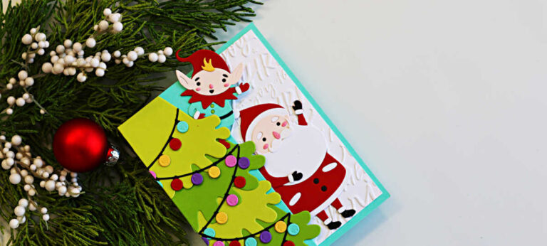 op-down view of a Merry Shuffle Single Z-Fold Christmas card featuring a layered green Christmas tree decorated with colorful lights, a playful elf peeking from behind the fold, and a cheerful Santa on an embossed white background. The card is displayed beside festive greenery and a red Christmas ornament.