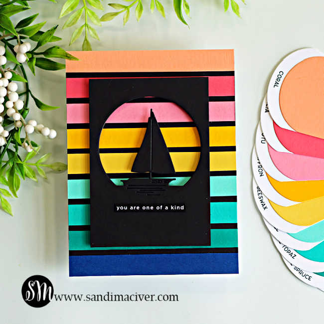 Handmade retro sailboat card featuring colorful horizontal cardstock stripes in coral, pink, yellow, aqua, teal, and navy, with a black sailboat silhouette inside a circular die-cut window. Coordinating Spellbinders ColorWheel cardstock swatches are displayed beside the finished card.