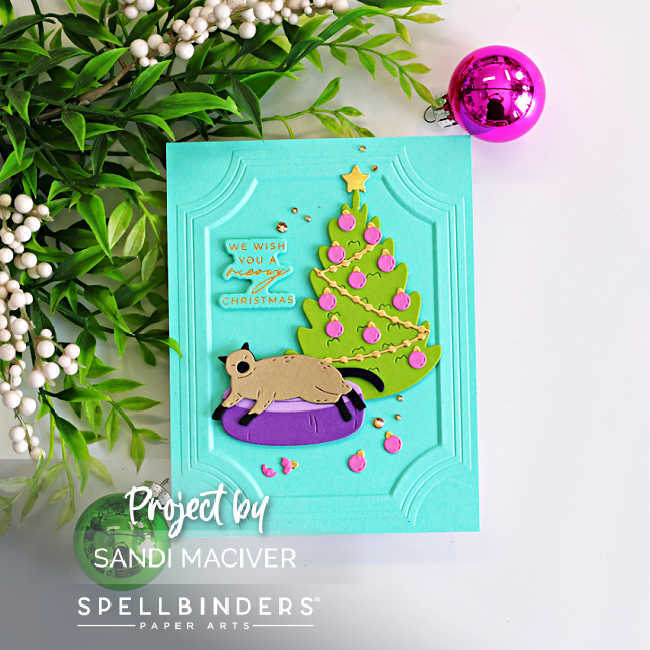 Handmade Christmas card featuring Yana's Christmas Cats from Spellbinders. A die-cut cat lounges in a purple pet bed beside a decorated Christmas tree on a turquoise panel embossed with the A2 Ornate Molded Frame 3D Embossing Folder. The card is finished with a gold-foiled "We Wish You a Meowy Christmas" sentiment, scattered ornaments, and gold embellishments.