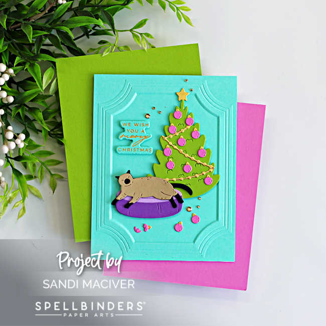 Handmade Christmas card featuring Yana's Christmas Cats from Spellbinders. A die-cut cat naps in a purple pet bed beside a decorated Christmas tree on a turquoise panel embossed with the A2 Ornate Molded Frame 3D Embossing Folder. The card includes a "We Wish You a Meowy Christmas" sentiment and is accented with gold embellishments and pink ornaments.