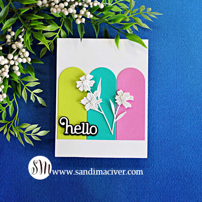 Handmade card featuring three colorful nesting arch panels in lime green, teal and pink, decorated with delicate white wildflowers and a bold “hello” sentiment.