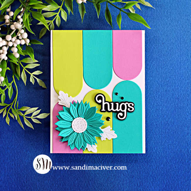 Handmade card featuring a staggered wallpaper pattern created with Peridot, Teal Topaz and Orchid nesting arches, finished with a dimensional teal flower, white leaves and a bold “hugs” sentiment.