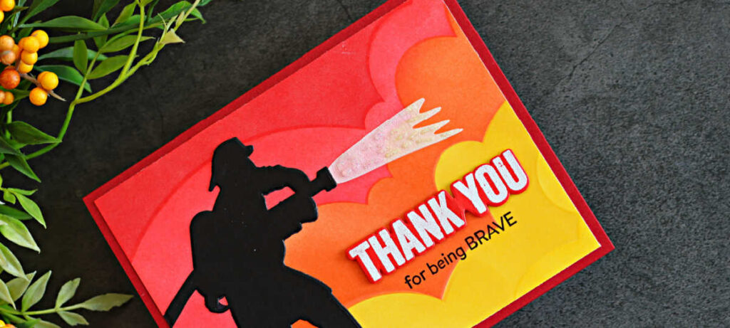 Handmade firefighter thank you card featuring a black die-cut firefighter silhouette spraying sparkling water over a red, orange and yellow ink-blended background, with the sentiment “Thank You for being Brave.”