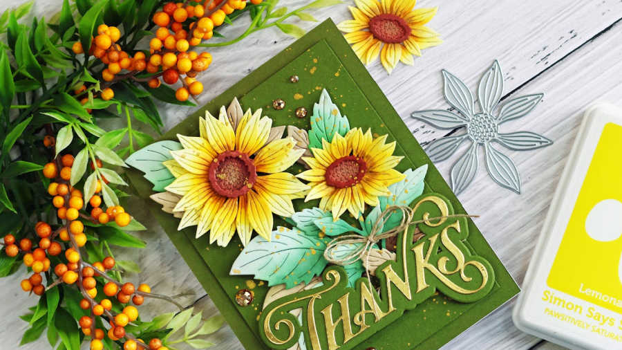 Handmade sunflower thank you card featuring layered yellow die-cut sunflowers, aqua green leaves, an olive green background, gold accents, and a large gold Thanks sentiment.