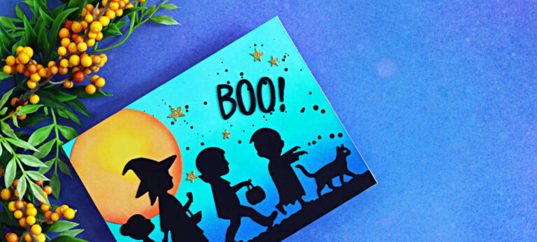 Colorful Halloween card featuring black trick-or-treat silhouettes against a bright blue ink-blended sky, with a glowing yellow-orange moon, gold stars, black splatter, and a bold “BOO!” sentiment.