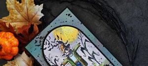 Tim Holtz The Scarecrow Halloween card featuring the new coordinating dies, with a colorful die-cut scarecrow layered over a distressed moonlit cornfield and flying bats.