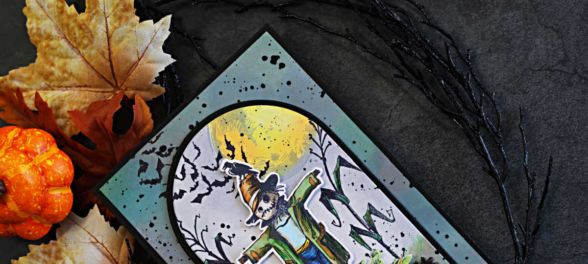 Tim Holtz The Scarecrow Halloween card featuring the new coordinating dies, with a colorful die-cut scarecrow layered over a distressed moonlit cornfield and flying bats.