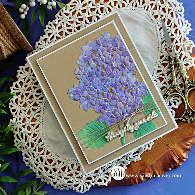 Handmade hydrangea card featuring purple stenciled flowers and green leaves on Kraft cardstock, layered with a white mat and finished with natural twine and an “Always by your side” sentiment.