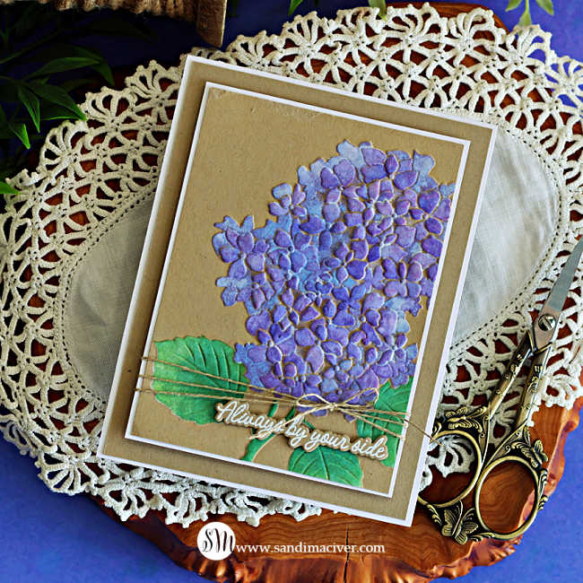 Handmade hydrangea card featuring purple stenciled flowers and green leaves on Kraft cardstock, layered with a white mat and finished with natural twine and an “Always by your side” sentiment.
