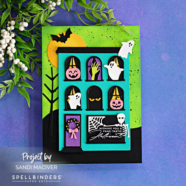 Fang-tastic Halloween card featuring a turquoise haunted house filled with ghosts, pumpkins, a skeleton, spiderweb and spooky details against a bright green ink-blended background.