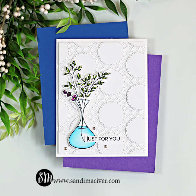 Handmade white card featuring a stitched circle geometric background with leafy stems and purple flowers in a turquoise vase, layered over blue and purple cardstock.