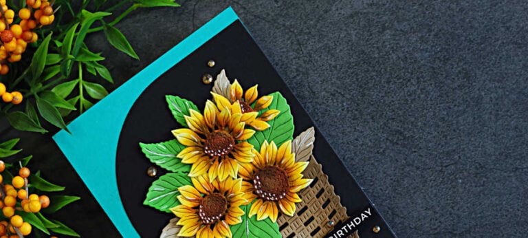 Close-up of a handmade birthday card featuring traditional golden yellow sunflowers in a woven basket, layered over a bold black Squarevel die-cut mat and teal card base.